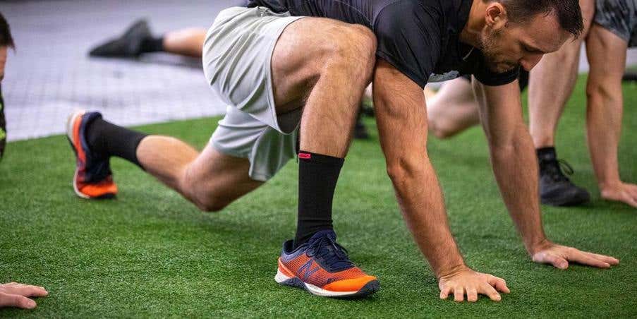 A man in a gym stretching his hamstrings.