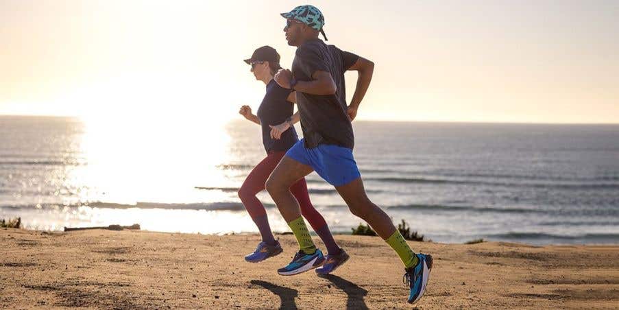 Two people running on the seashore sunset.