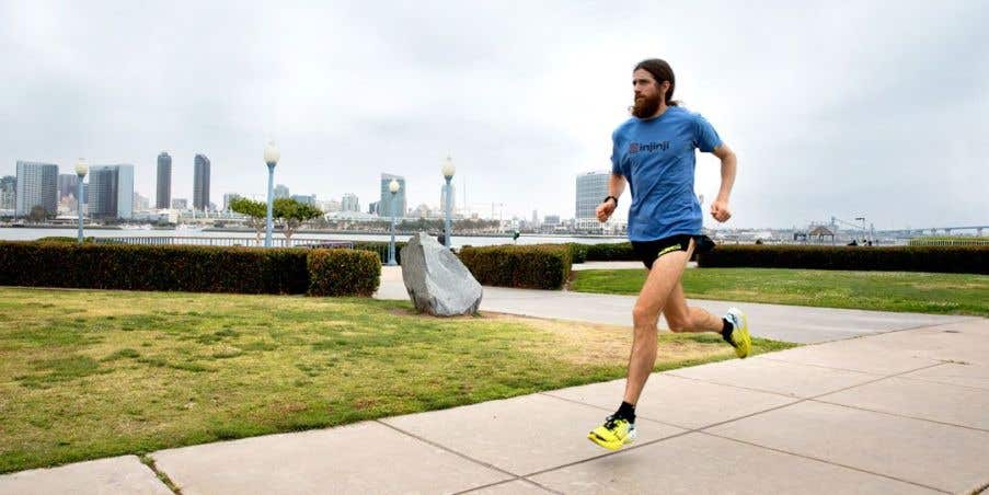 Elite athlete Mike Wardian running down a large sidewalk with the city line in the background.