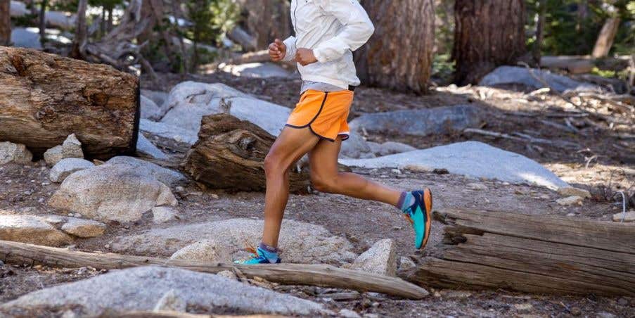 Trail runner traversing rocks and logs. 