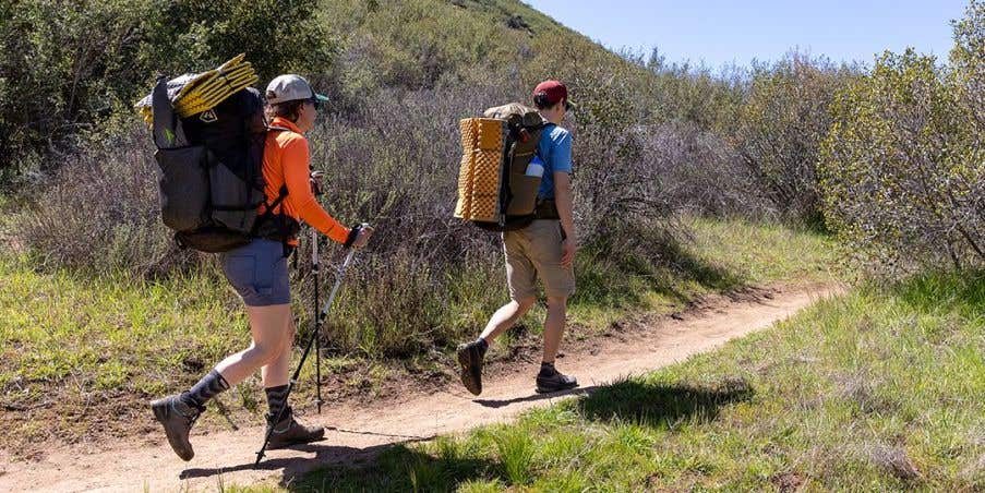 Two backpackers on a trail wearing their Outdoor Midweight Merino wool socks. 