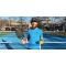 Mike Wardian with a pickleball paddle and ball standing on a pickleball court. 