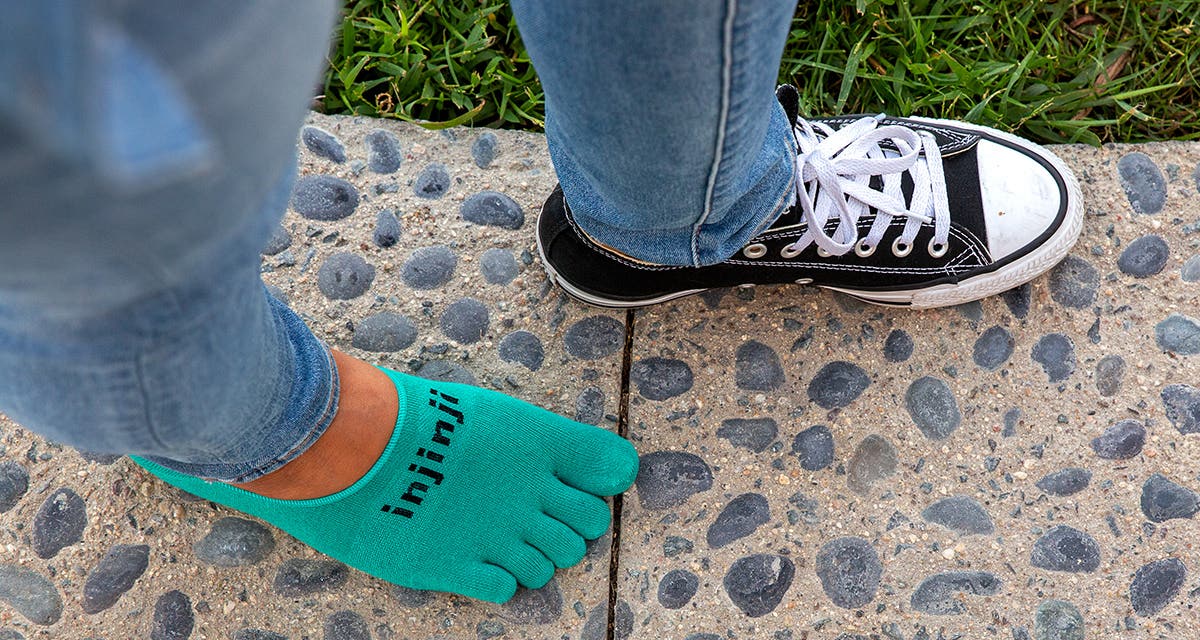 A closeup shot of a woman's feet wearing Injinji Everyday Lightweight Hidden Upcycled Cotton toesocks in Gem