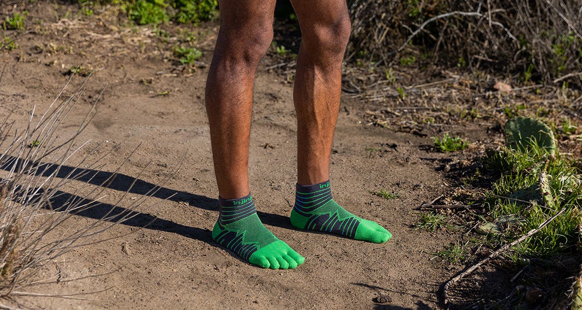 A man standing on a dirt path wearing Injinji Ultra Run Mini-Crew socks in Emerald.