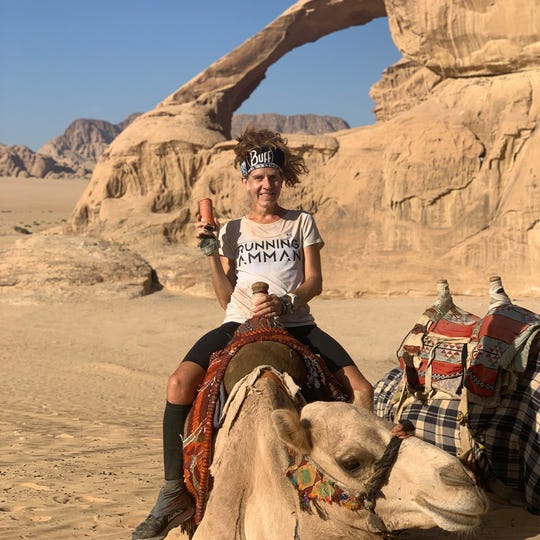 Amy Sproston in the desert sitting on a back of a camel