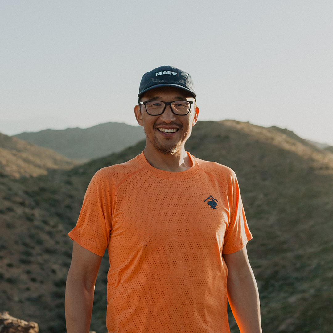 Team Injinji athlete Phil Shin standing outside smiling with mountains in the background. 