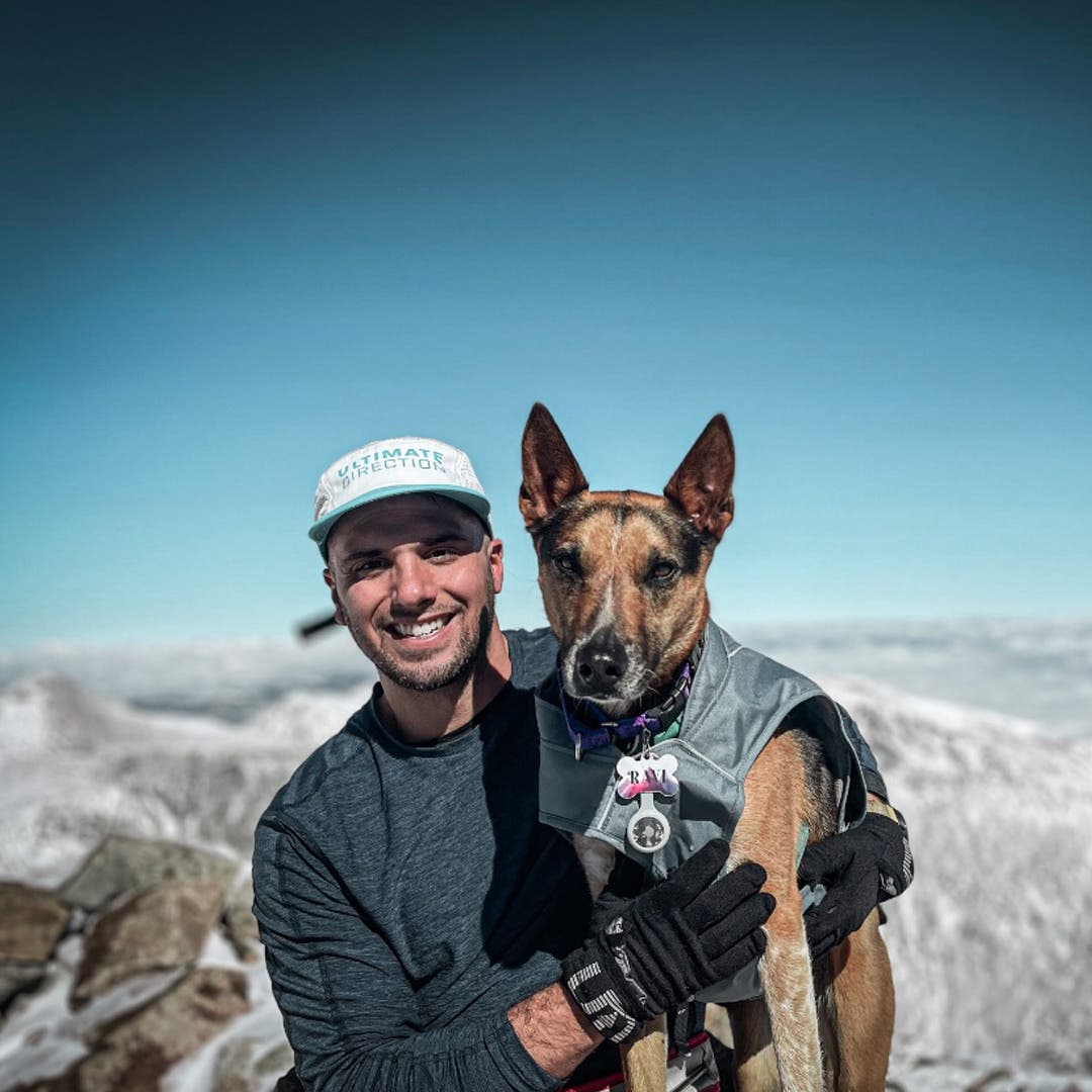 Team Injinji Athlete James Lauriello sitting at the top of mountain peak with his dog.