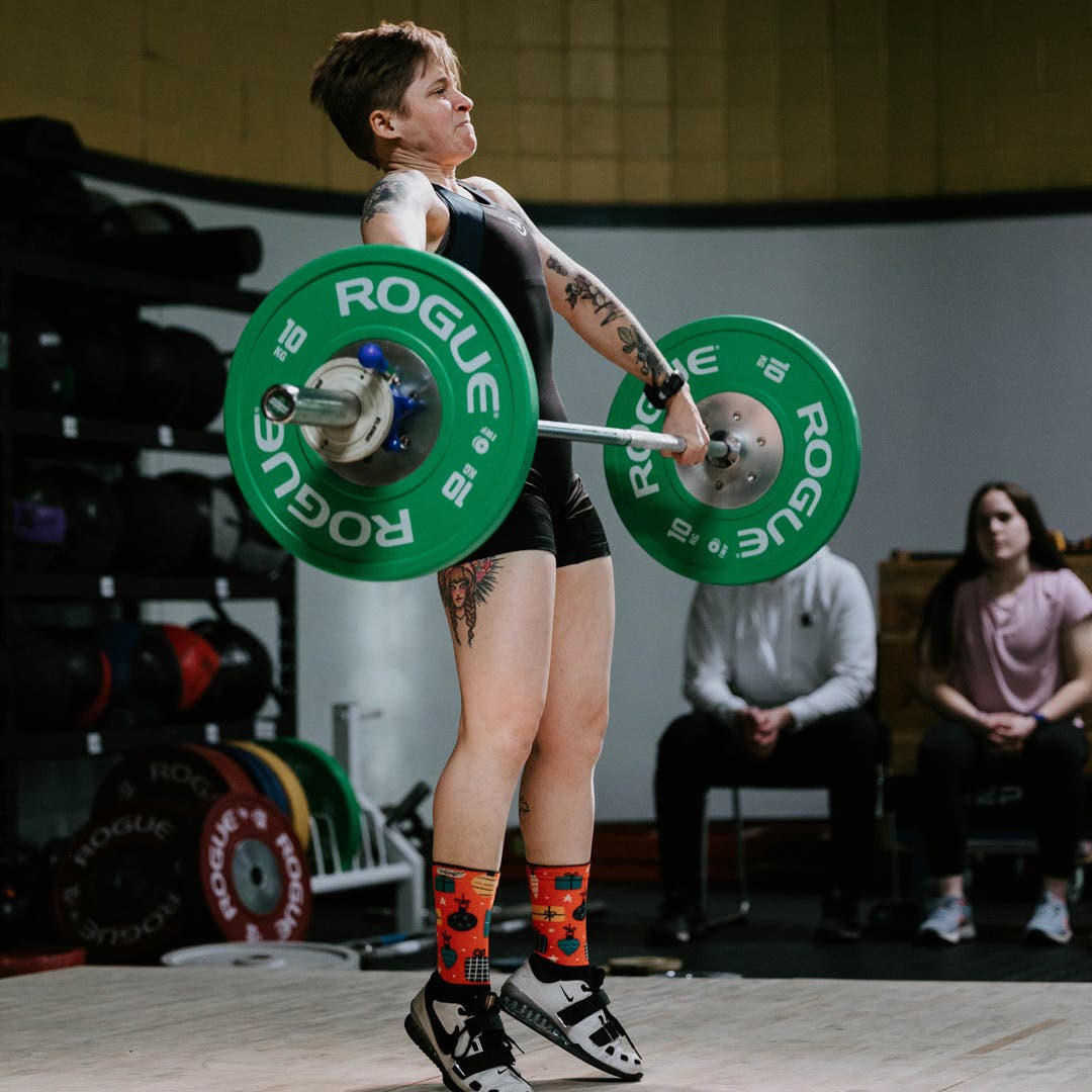 Team Injinji Athlete Jessica Storrison-Carmean lifting up a large barbell during a weightlifting competition.