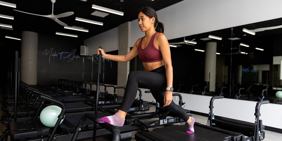 A woman practicing pilates in wearing Injinji Grip full foot no-show socks in a pilates studio.