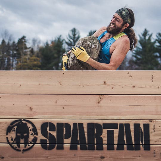 Ultra runner Mike Wardian holding a huge stone in hands during Spartan Games competition