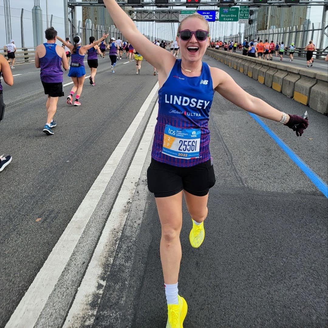 Lindsey LaVeck with her arms outstretched excitedly while standing on a bridge during the New York City marathon.