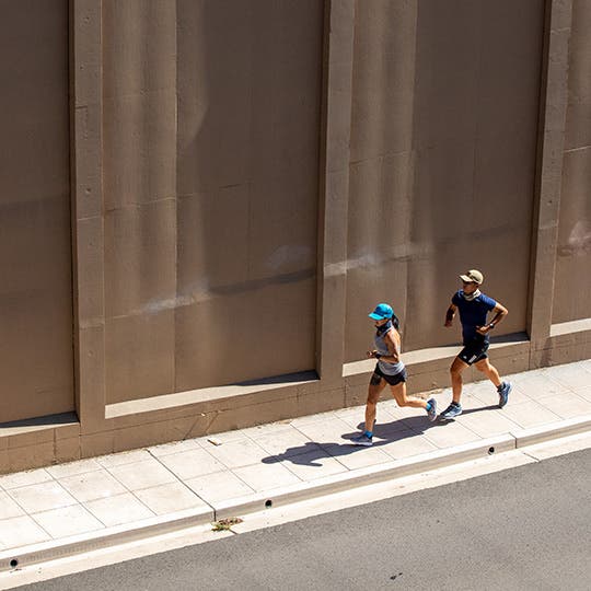 Man and woman running on the sidewalk in the city environment