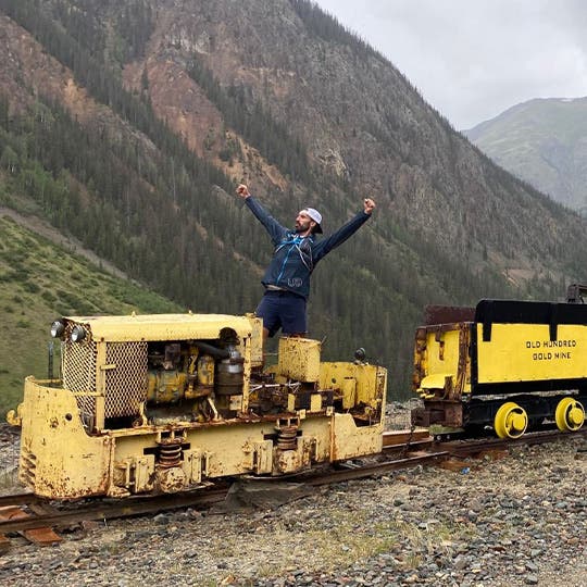 Peter showing off his goofy personality by standing in a miniature train among the mountains. 