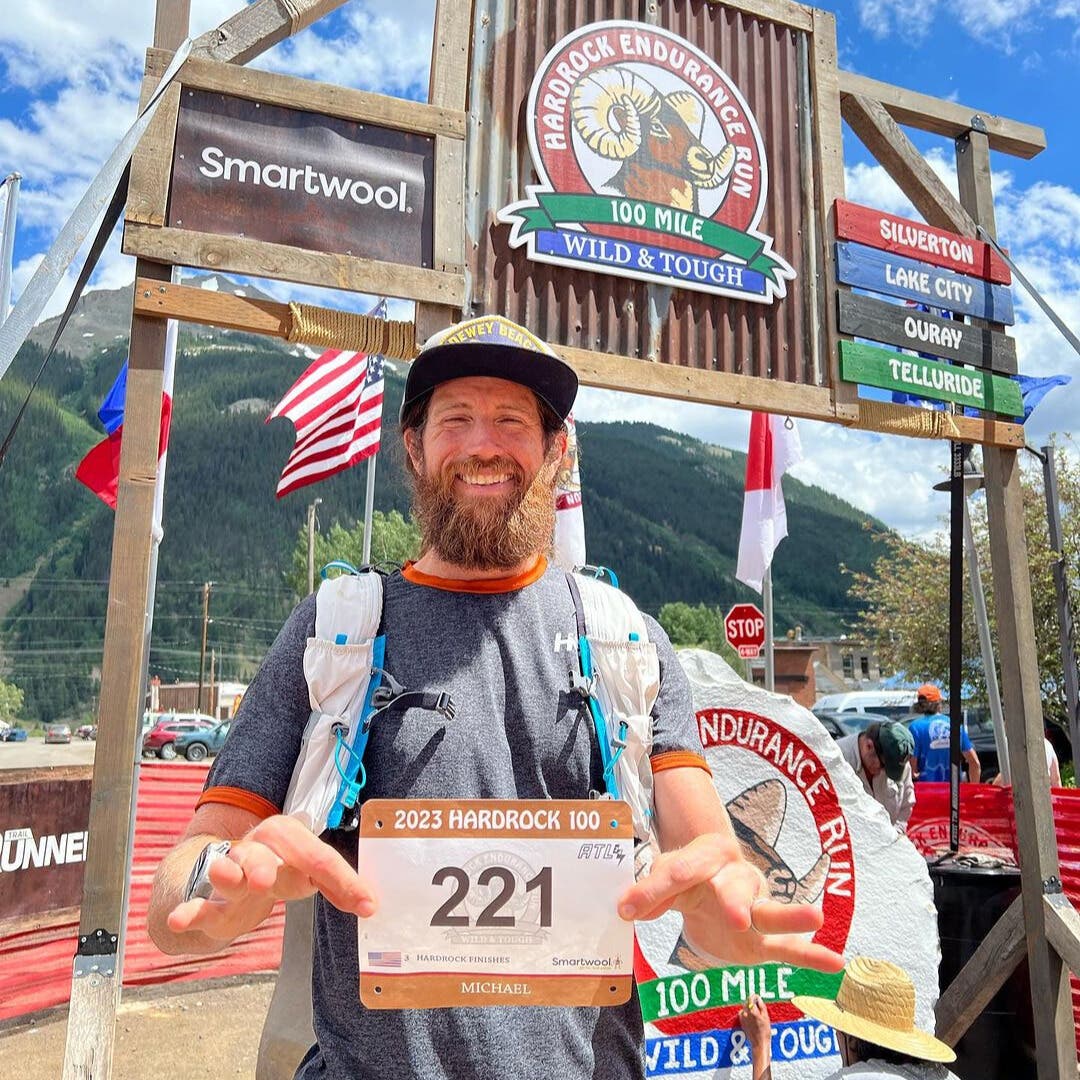 Mike Wardian at the Hardrock 100 starting line holding up his race bib.