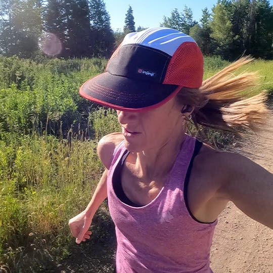 Tara Warren in pink singlet and cap running in natural environments