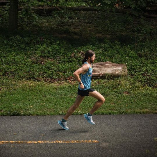 Mike Wardian running on the asphalted forest road seen from the side