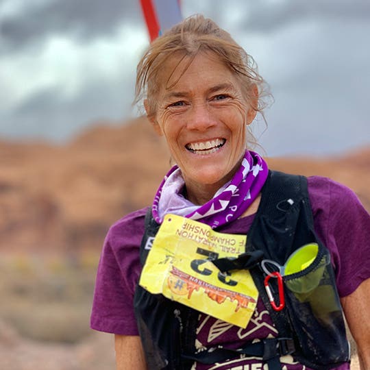 Smiling Anita Ortiz in purple sports clothing with a participant's number on the chest