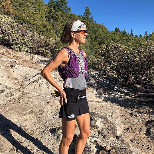 Smiling Meghan Canfield standing on the stony ground in the mountains