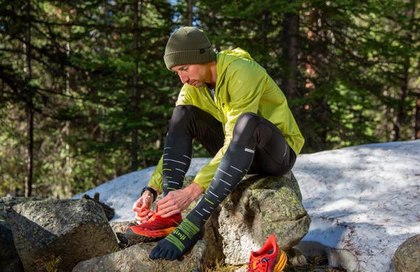 Trail Runner finishing putting on the new Injinji Snow Over the Calf toesocks in shadow..
