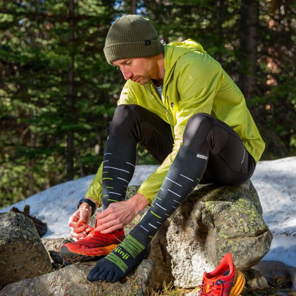 Trail Runner finishing putting on the new Injinji Snow Over the Calf toesocks in shadow..