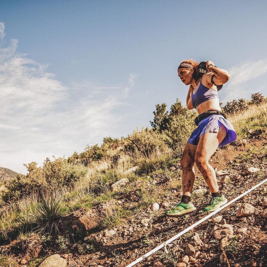 Alexandra Mueller carrying a weighted bucket over her shoulder during an obstacle course race.