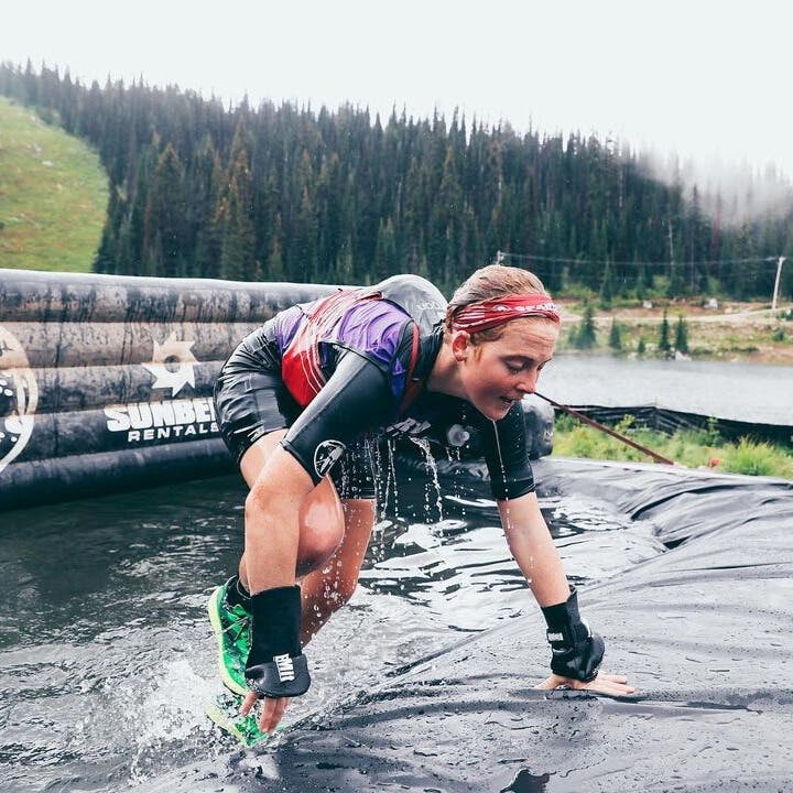 Alexandra Mueller carrying a weighted bucket over her shoulder during an obstacle course race.