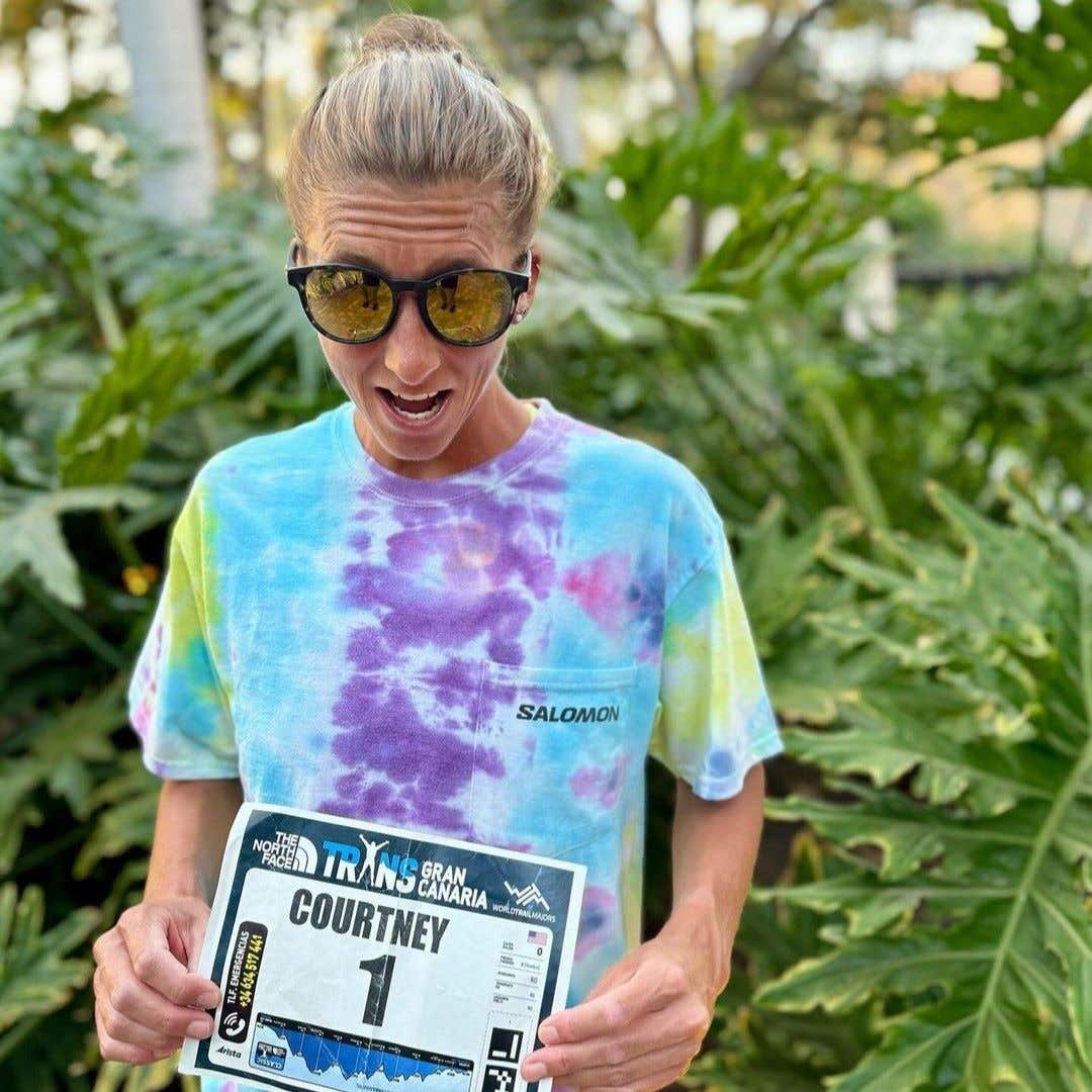 Team Injinji athlete Courtney Dauwalter holding a race bib.