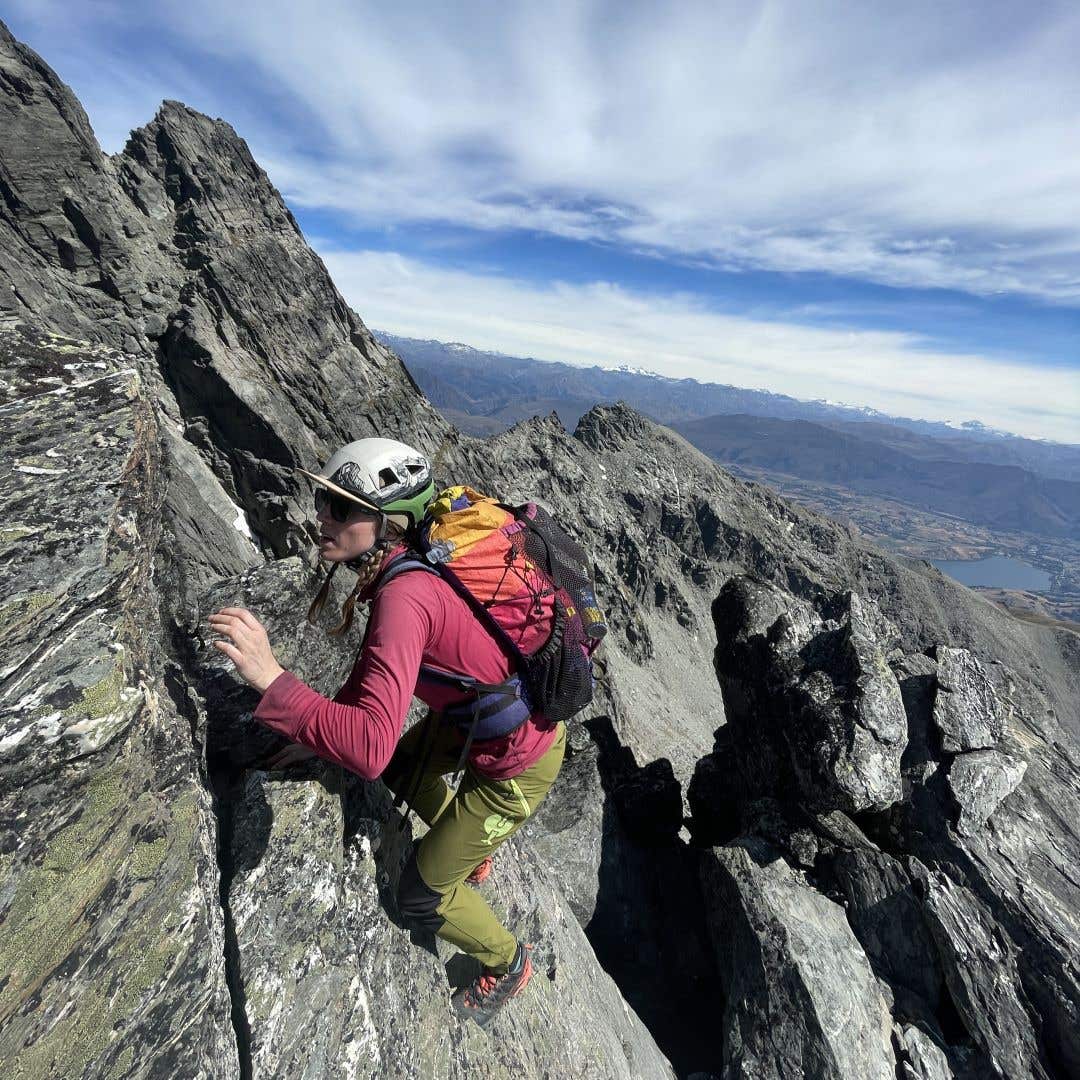 Team Injinji Athlete Caroline Himbert climbing up the side of jagged mountain.