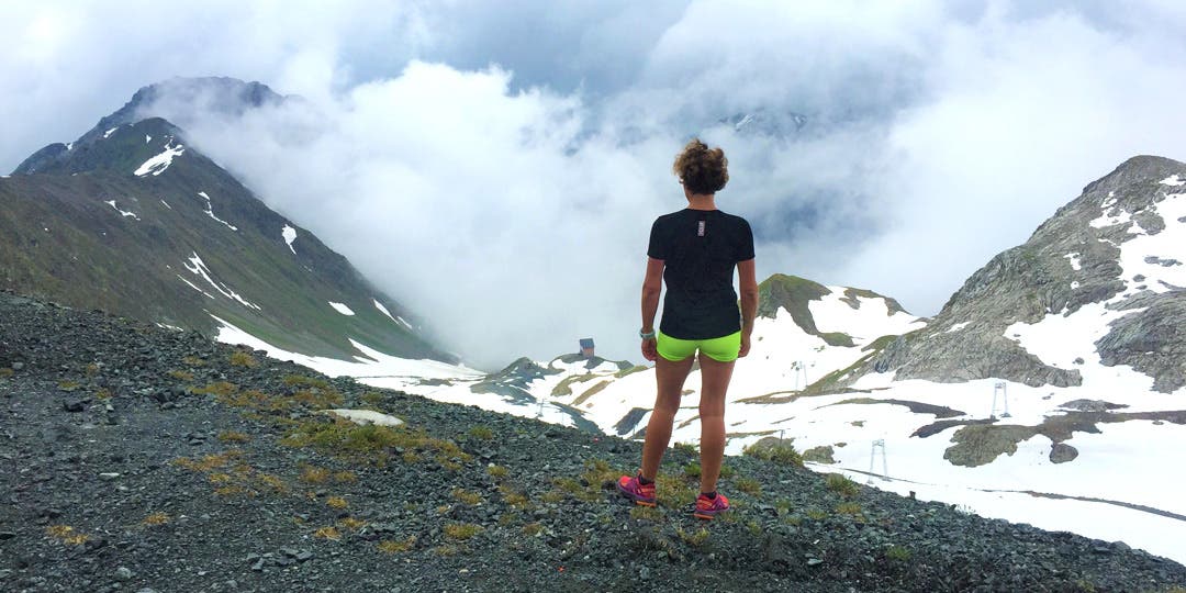 Race director Francesca Conte seen from the back standing and looking at the mountains with snow on top