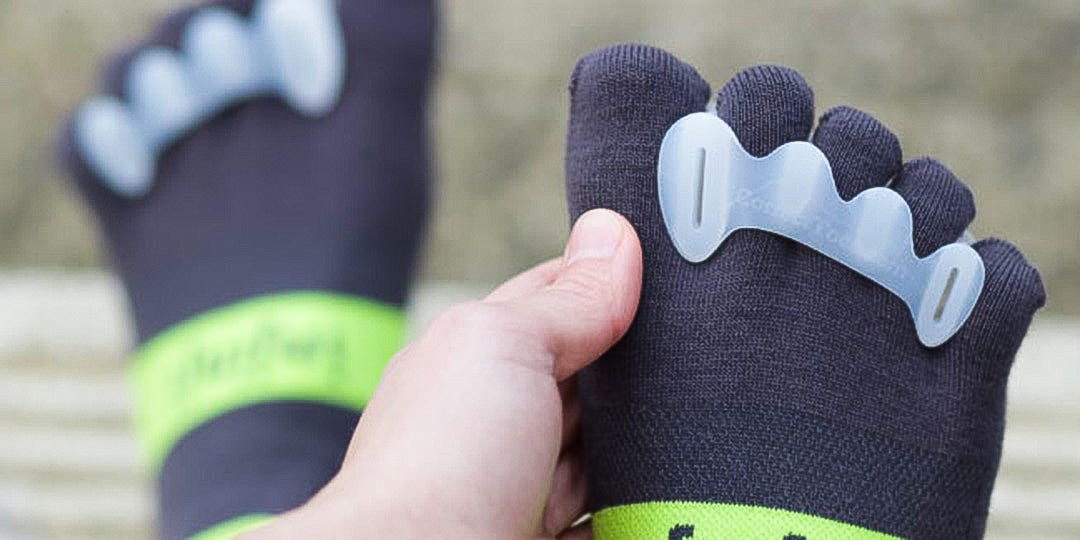 Close-up view on a person's foot and toes wearing Injinji toesocks and a Correct Toes toe separator. 