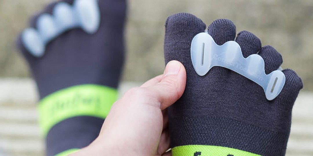 Close-up view on a person's foot and toes wearing Injinji toesocks and a Correct Toes toe separator. Close-up view on a person's foot and toes wearing Injinji toesocks and a Correct Toes toe separator.
