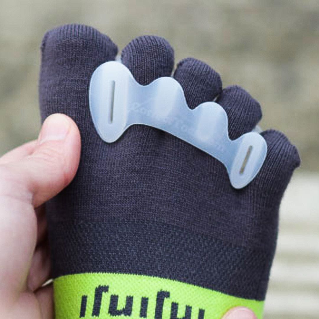 Close-up view on a person's foot and toes wearing Injinji toesocks and a Correct Toes toe separator. Close-up view on a person's foot and toes wearing Injinji toesocks and a Correct Toes toe separator.