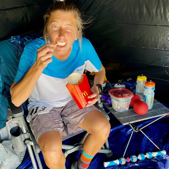 Courtney Dauwalter sitting in a tent and eating McDonalds french fries.