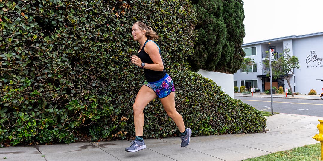 A woman running on a sidewalk in a suburban area.
