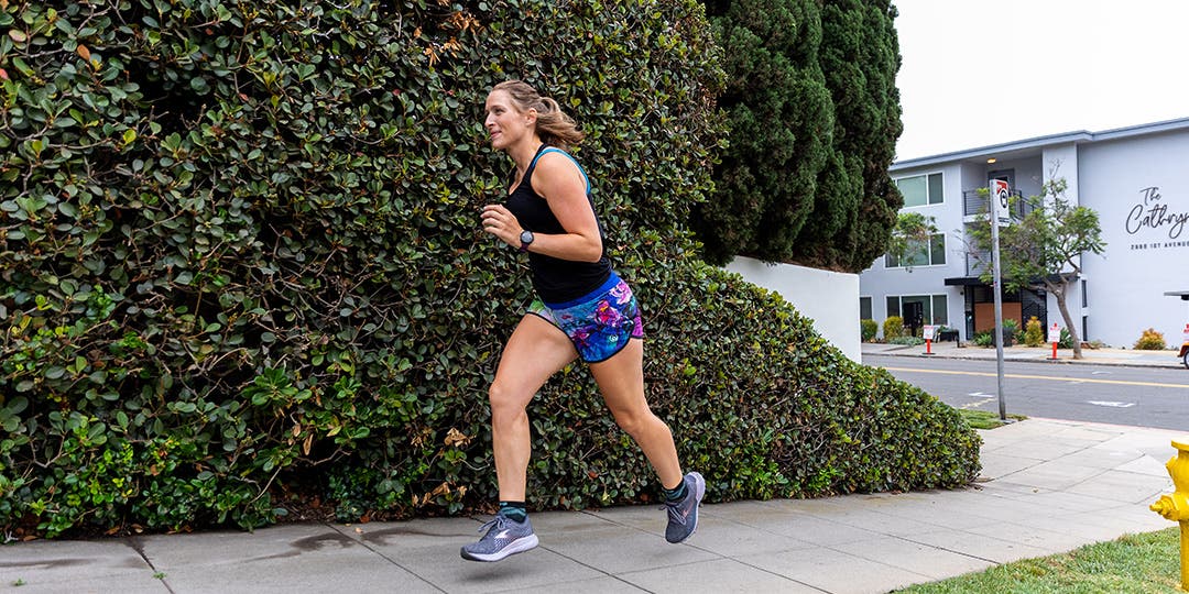 A woman running on a sidewalk in a suburban area. 