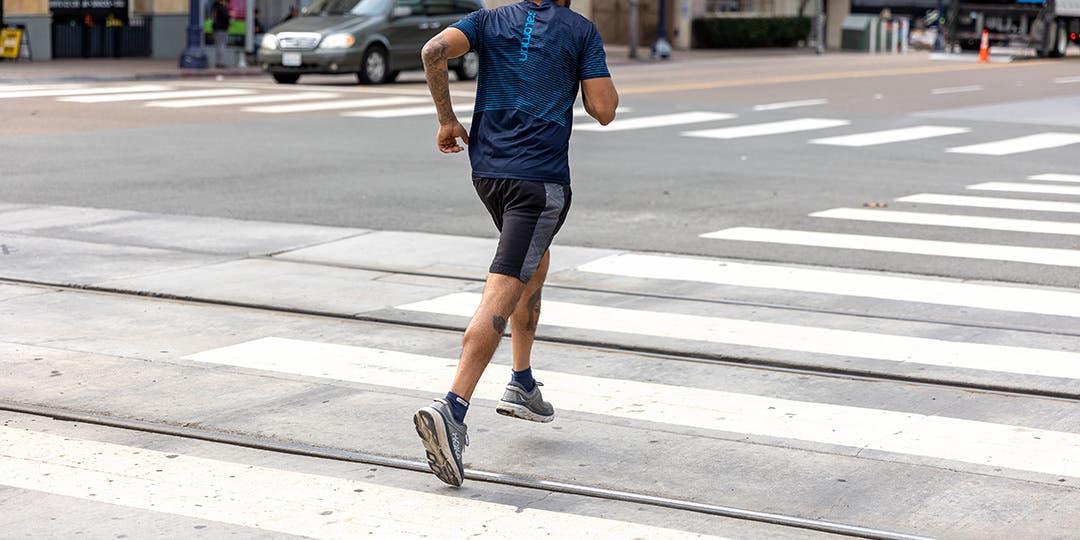 A man running through a cross walk in a metro area. 