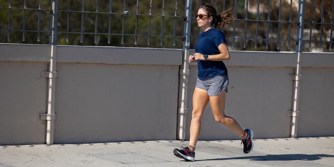 A woman running across a city bridge.