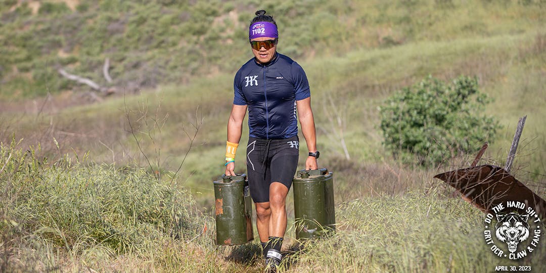 Justin Nucum carrying heavy weights while running in a field.
