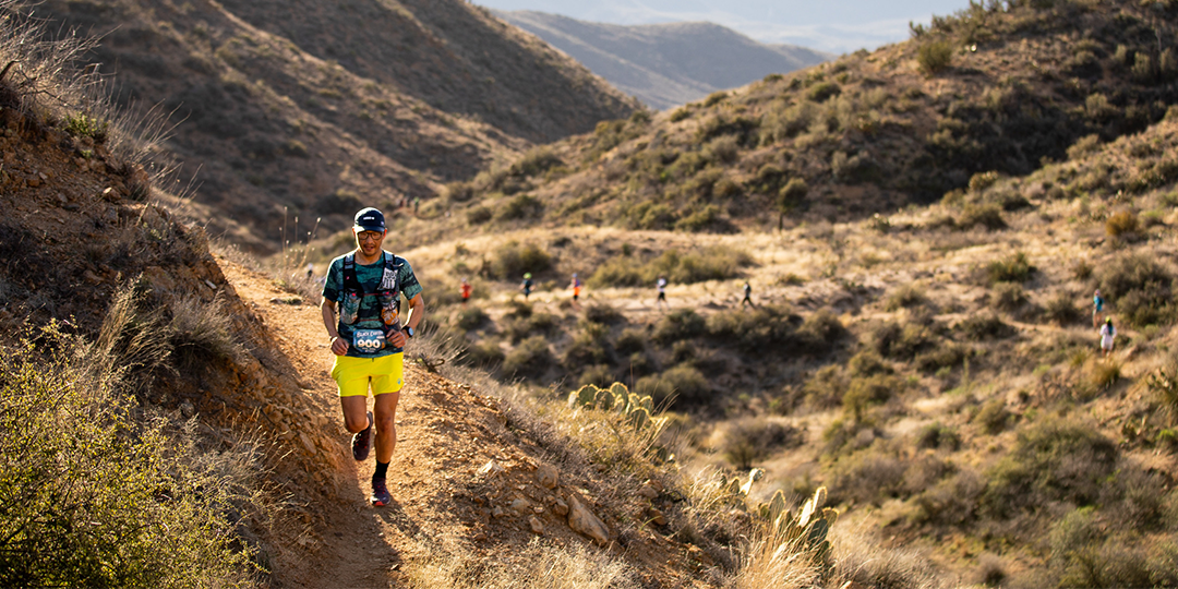 Team Injinji athlete Phil Shin running on a single track trail on a moutainside.