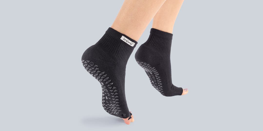 Closeup of someone standing on their toes wearing Injinji Grip Toeless Mini-Crew socks.