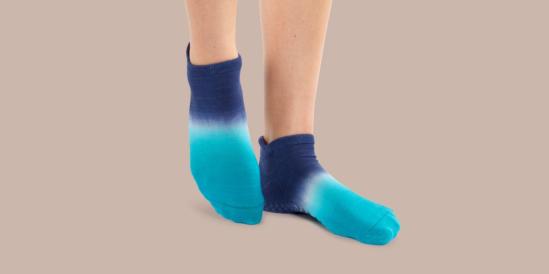 Closeup of someone pointing their toes wearing Injinji Grip Full Foot No-Show socks.