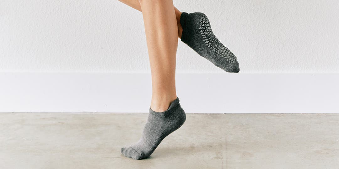 A person standing in a ballet position pointing their toes wearing Injinji Grip Full Foot No-Show socks.