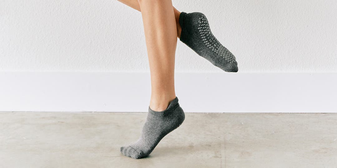 A person standing in a ballet position pointing their toes wearing Injinji Grip Full Foot No-Show socks. 