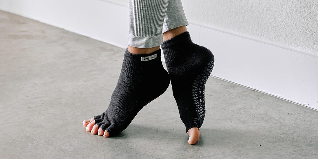 A person standing in a ballet position pointing their toes wearing Injinji Grip Toeless Mini-Crew socks. 