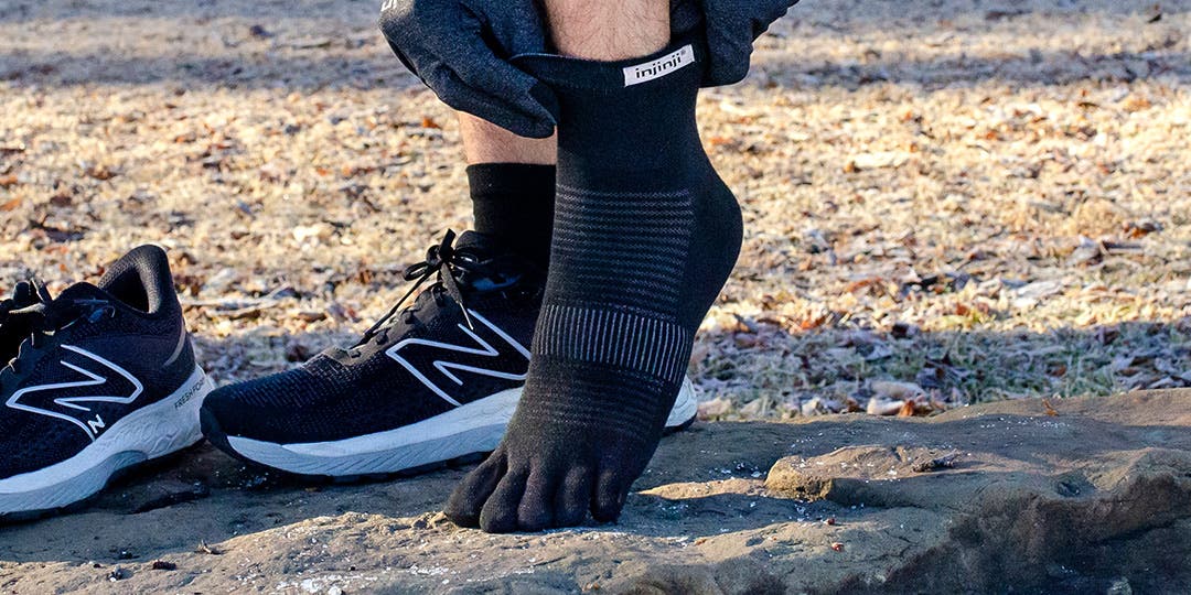 Close up view of someone's feet as they adjust their Injinji Run Lightweight Mini-Crew toesocks.
