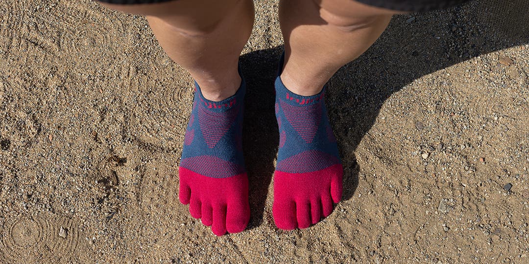 Looking down on a person's foot wearing Injinji Women's Ultra Run No-Show toesocks in Berry. 