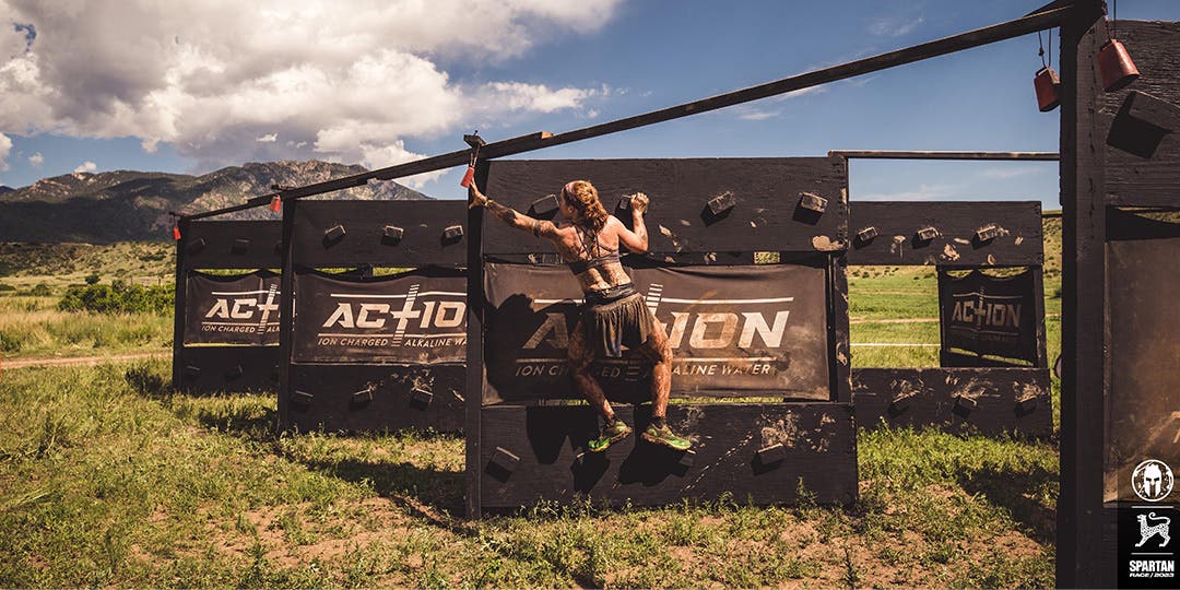 Cali Schweikart climbing up a wall during an obstacle course competition.