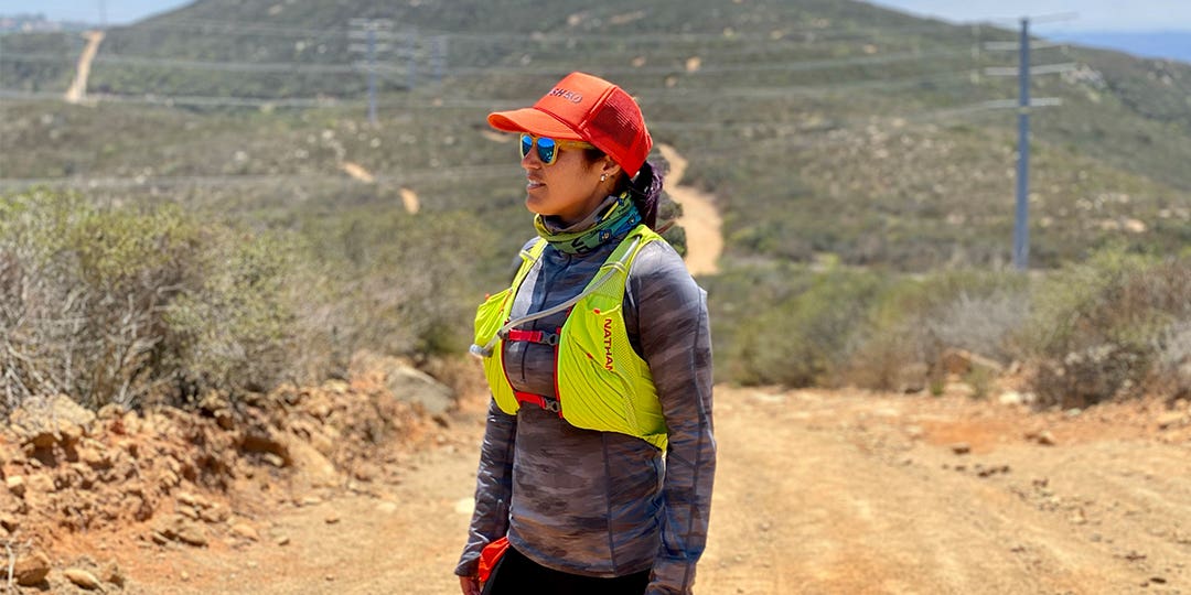 Isabella Janovick wearing an orange cap and sunglasses standing on the mountain road