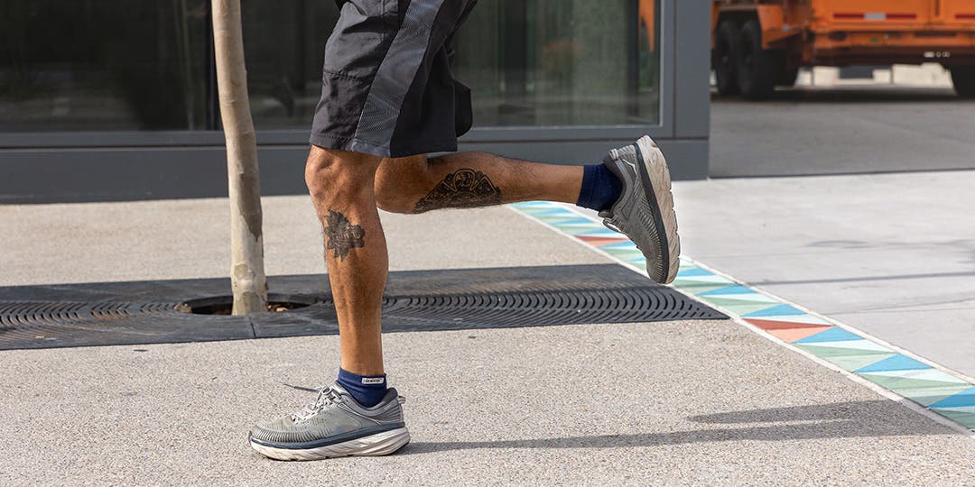 A man running on the sidewalk wearing Injinji socks.