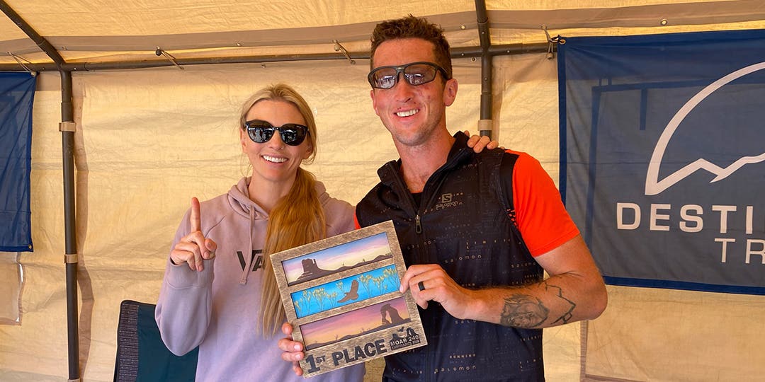 Smiling Mike McKnight standing near a woman and holding a "first place" sign in his hands